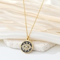 Detailed macro view of gold Evil Eye pendant with black enamel and crystals on white stone - Black Round Eye