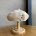 Beige wool beret for women featuring silver metal hook buckles on a wooden stand - M (56-58cm) / Silver Buckle - Beige