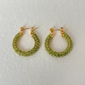 Golden round earrings with green pave-set zircons on textured white surface - Light Green