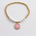 Close-up of pearl and gold bead bracelet featuring a pink zircon smiley face charm - Pink