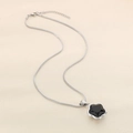 Detail of silver snake chain with a black five-petal flower pendant on beige surface - Steel Color (KN288351-KFC)