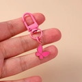 Vista detallada de un llavero con colgante de mariposa esmaltada rosa en la mano - Mariposa Rojo Rosa