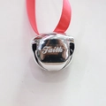 Close-up of a silver metal bell featuring a red ribbon and engraved Faith lettering - Faith