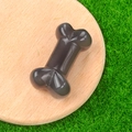 Polished black crystal agate bone carving placed on a wooden base over green grass - Grey Agate