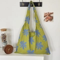 Gros plan d'un grand sac cabas en toile à fleurs vert et bleu suspendu à un crochet - Vert