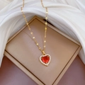 Vue détaillée du collier coeur avec cristal rouge et chaîne dorée sur fond de soie - Pendentif En Cuivre Et Acier Titane Rouge G511