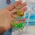 Flower shaped liquid sand keychain with green glitter and colorful beads - Green with Bell