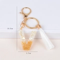 Detail of letter V keychain with gold foil, white tassel, and 10.5cm size dimensions - Letter V
