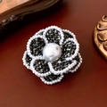 Vista dettagliata della spilla a fiore in tweed con perle su sfondo di pelle scura - Spilla 48# - Nero - Fiore