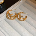 Macro shot of gold-plated metal letter E earrings on a grey velvet jewelry display tray - Hollow Letter C-Shaped Style (HE16068) / Gold