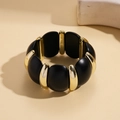 Details eines breiten Stretch-Armbands mit matten schwarzen und goldfarbenen Segmenten - Schwarz