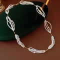 Nahaufnahme der weißen Perlenkette mit Goldkette auf grünem Samtkissen präsentiert - Weiß-Gold