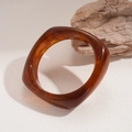Close-up of tortoise shell resin bangle with irregular geometric square shape on stone - Rounded Square Tortoise Pattern Style