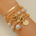 Detail of layered gold snake chain and pearl bracelet set with OT toggle clasp on wrist - Gold (1938)