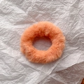 Detail of soft orange faux rabbit fur scrunchie on white textured paper background - Orange
