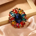 Colorful rhinestone flower brooch with blue center stone on gold alloy base - Colorful