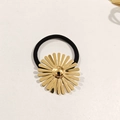 Détail d'une breloque marguerite dorée sur un élastique à cheveux noir au fini poli brillant - Marguerite en Métal