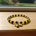Beaded bee bracelet with yellow and black translucent beads on a wooden surface - Honeybee Beaded Bracelet