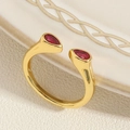 Nahaufnahme goldener Bambus-Ring mit zwei birnenförmigen roten Zirkonia auf weißem Teller - Wassertropfen Roter Zirkon Ring