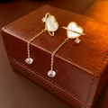 Macro detail of gold-plated heart earrings with mother-of-pearl and crystal tassels - Gold