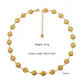 Vue macro des pendentifs soleil dorés sur collier en acier avec les détails de taille - Collier Or