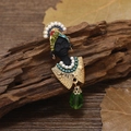 Exotic black portrait brooch with pearls and green teardrop gem on wood background - Female with Earrings