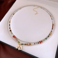 Detail view of colorful beaded necklace with a gold elephant pendant on a white velvet stand - Colorful