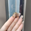 Golden beetle brooch featuring pink and purple rhinestones held by fingers - Purple