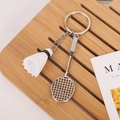 Close-up of a silver badminton racket and shuttlecock keychain on a wooden surface - Racket With Clasp / White