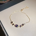 Detail of adjustable gold bracelet featuring purple oval zircons and crystal floral charms - Purple Oval / Gold
