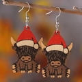 Vista detallada de pendientes de madera de vaca con gorros de Papá Noel en una rama - 1207-Vaca de las Tierras Altas