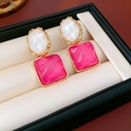 Detail von Goldohrringen mit weißen und rosa Steinen in einem Schmuckkästchen-Display - Rosarot