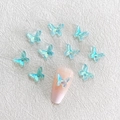 Light blue 3D aurora resin butterfly nail charms on a textured white background - Aurora Blue