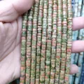 Close-up of natural unakite stone cylinder beads showing green and pink mineral texture - Unakite