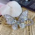 Goldene Schmetterling Haarklammer mit Zirkonia-Kristallen auf Vintage-Zeitungshintergrund - Zirkonia Schmetterling Pferdeschwanz Clip