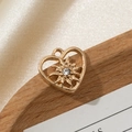 Dettaglio macro di un ciondolo a cuore dorato cavo con stella centrale e zircone lucente - Stile design traforato 4