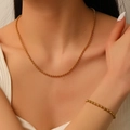 Golden stainless steel bead ball necklace and bracelet set worn by a model - Necklace + Bracelet / Gold Set