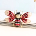 Elegant gold insect bee brooch with red and black enamel wings on an open book - Bee / Red