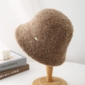 Detail of dark khaki lamb wool bucket hat with gold metal J&S logo on wooden stand - Mocha
