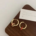 Detalle de pendientes de aro dorados con dijes de esmalte rojo sobre madera nogal - Cobre Bañado en Oro / Pendientes de Aro Individuales Rojos