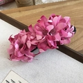 Dettaglio della molletta per capelli con fiori di stoffa rosa su sfondo di legno naturale - Rosa