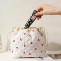 Action shot of putting hand cream into a white quilted cherry print drawstring bag - White Red Cherry