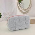 Detailed close-up of light blue quilted cloud makeup bag with a pink zipper contrast - Light Blue