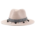 Détail d'un chapeau de paille beige avec ruban géométrique, pompons noirs et pièces argentées - Rose chair