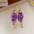 Golden fish shaped earrings with purple sequin scales on a beige textured tray - Koi Fish Style (HE27900) / Purple