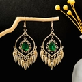 Close-up of vintage gold tassel earrings with green teardrop stone on wooden branch - Golden Green Style (E6091-14/Gold Green)
