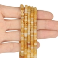 Hand holding multiple strands of orange abacus beads 4x2mm for jewelry making - 150 Pieces / Yellow Aventurine