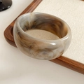 Detailed view of wide amber marble resin bangle with polished tortoiseshell texture - Gray