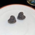 Vista macro de pendientes de corazón gris oscuro con cristales brillantes en un plato - Corazón Gris (Pin de Plata)