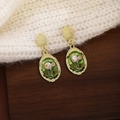 Detailed macro view of vintage gold earrings with green enamel and pearls on a sweater - Gold Base Green Enamel Pearl (E6465)